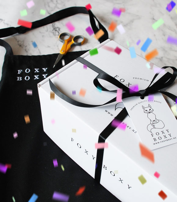 FOXY BOXY apron and FOXY BOXY gift box with confetti in the air
